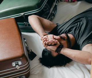 Tired ethnic man lying on bed during relocation in new house